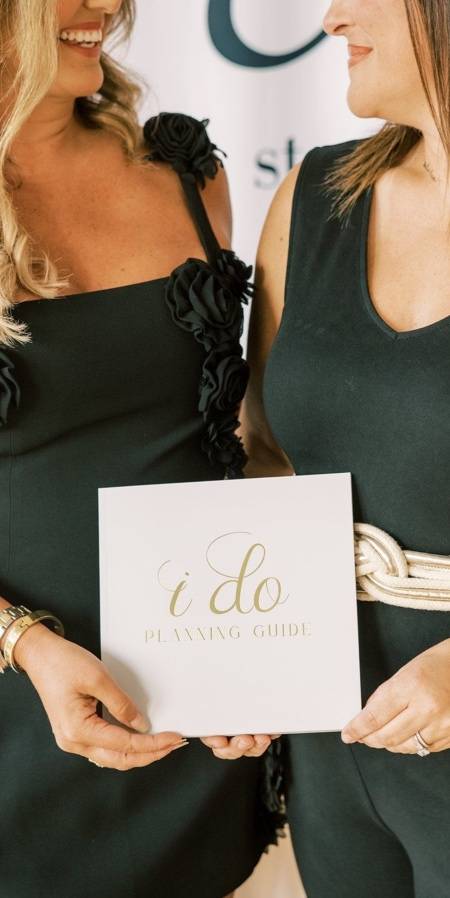 Models in a black costumes holding an I DO playing guide